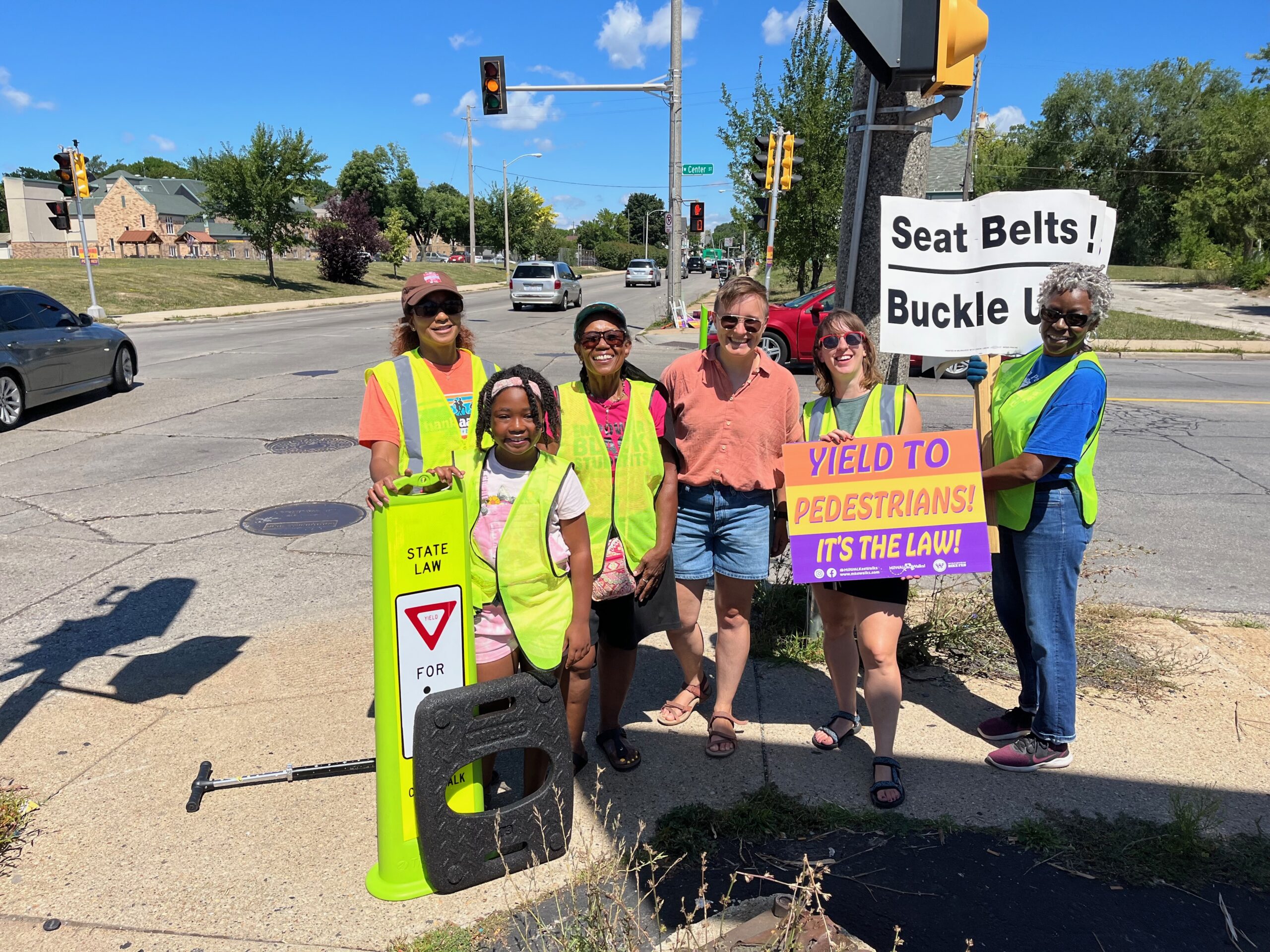 MilWALKee Walks volunteers hold signs at an intersection.